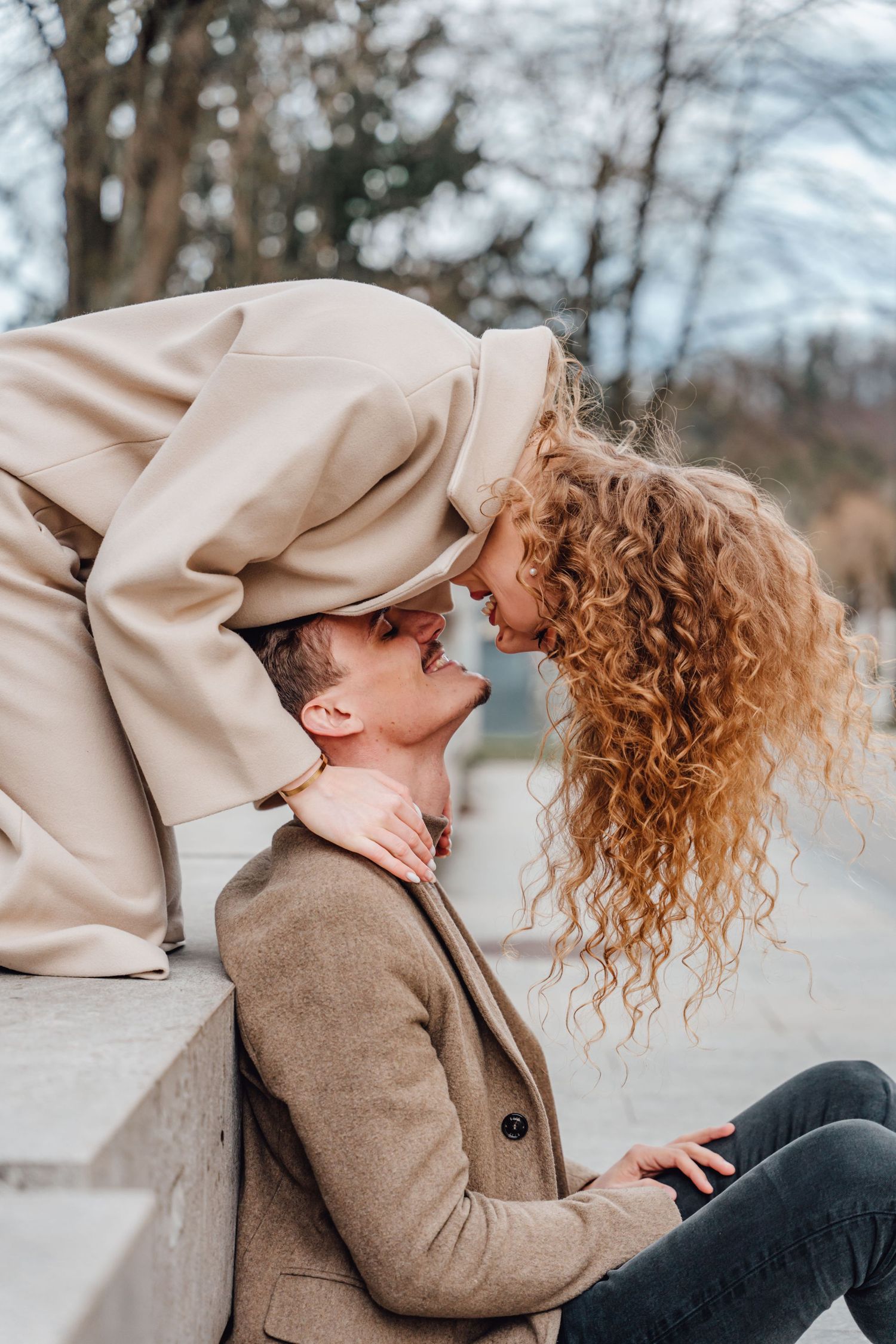 A romantic couple shares an intimate moment on concrete steps outdoors.