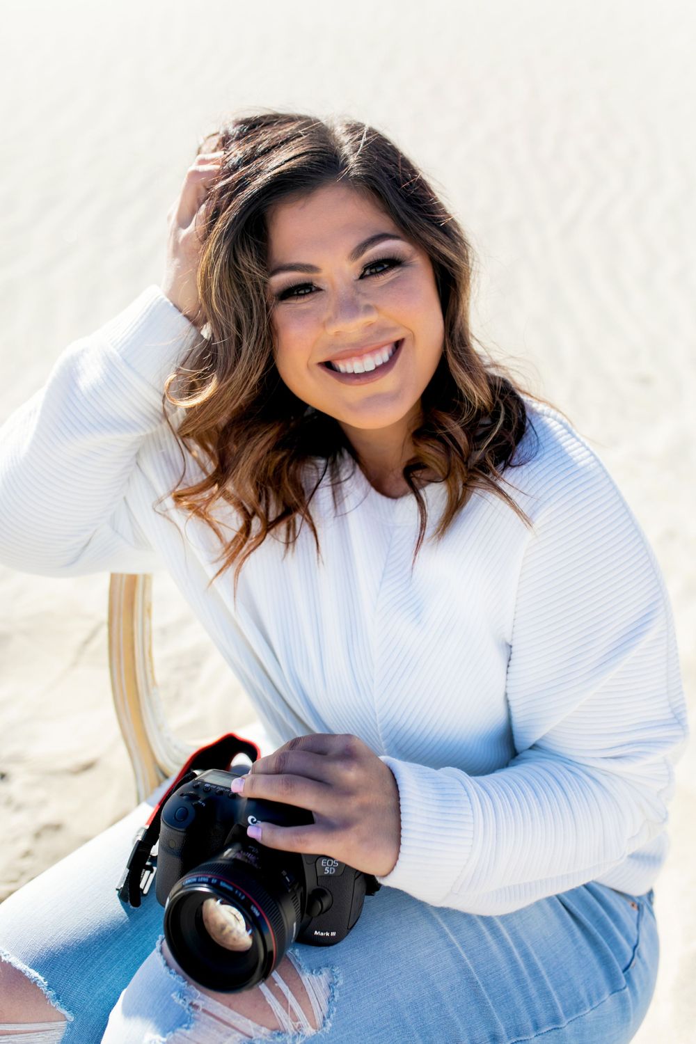 Hayley Lamas is sitting in a chair with a camera on her lap.