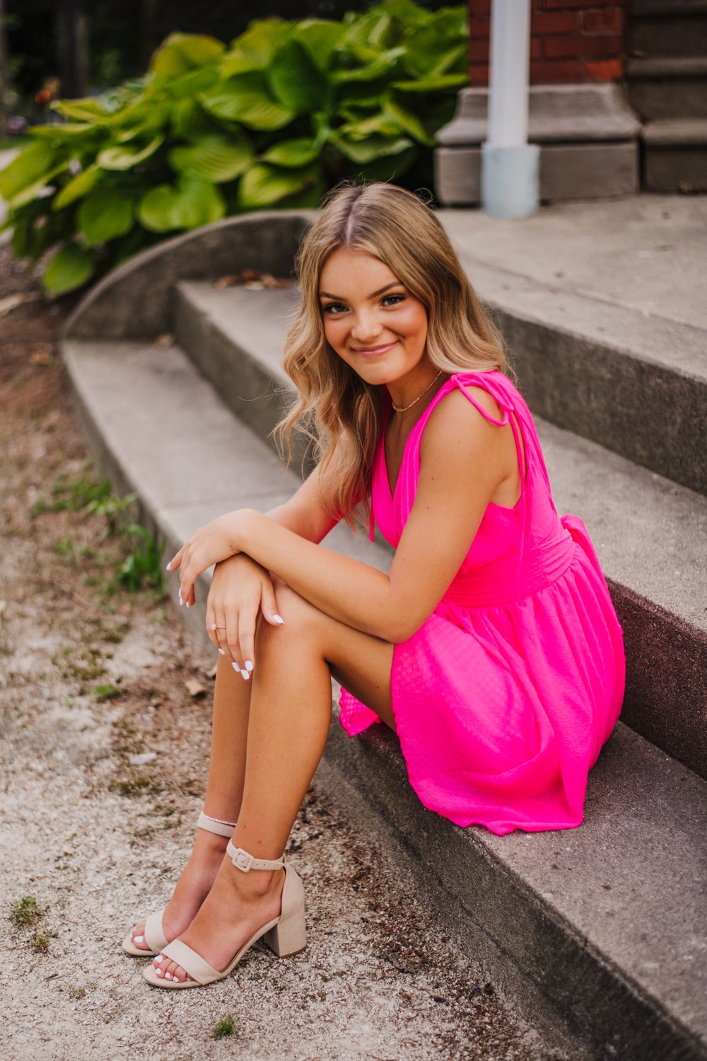 Summer fashion shoot on concrete steps with pink dress and silver heels.