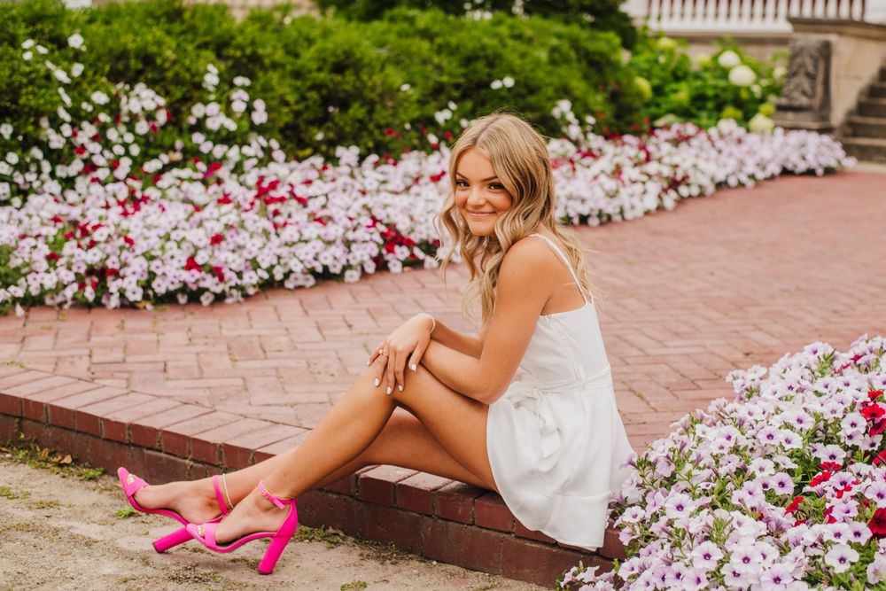 Outdoor portrait session near blooming pink and white flowers with classic architecture.