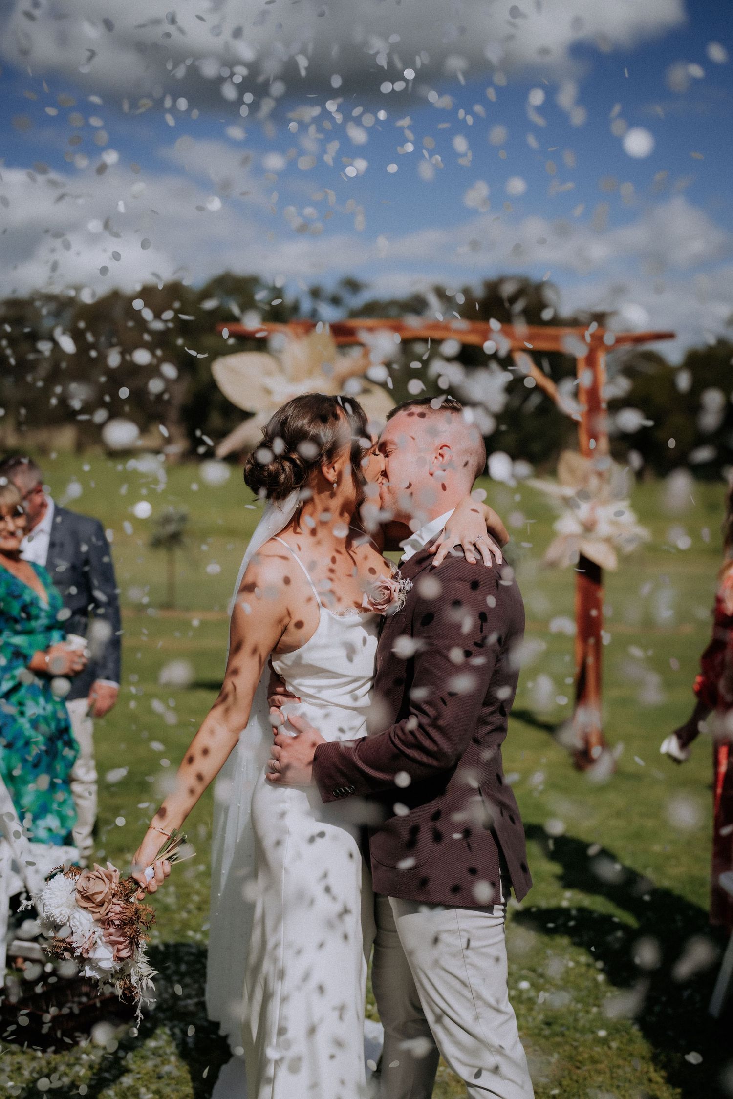 Joyful celebration with confetti falling during an outdoor wedding ceremony.