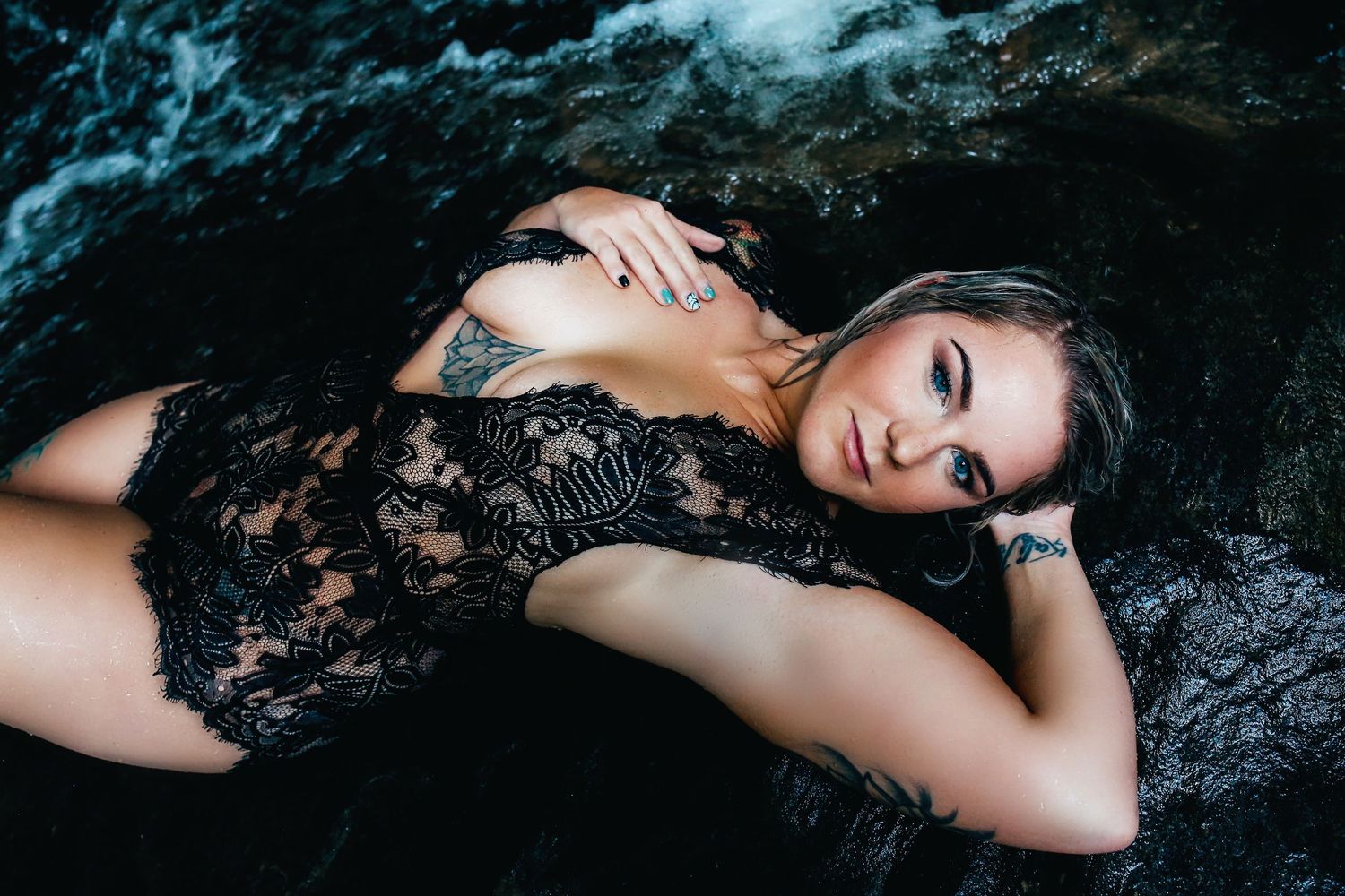 Atmospheric portrait on dark rocks with dramatic lighting and lace details.