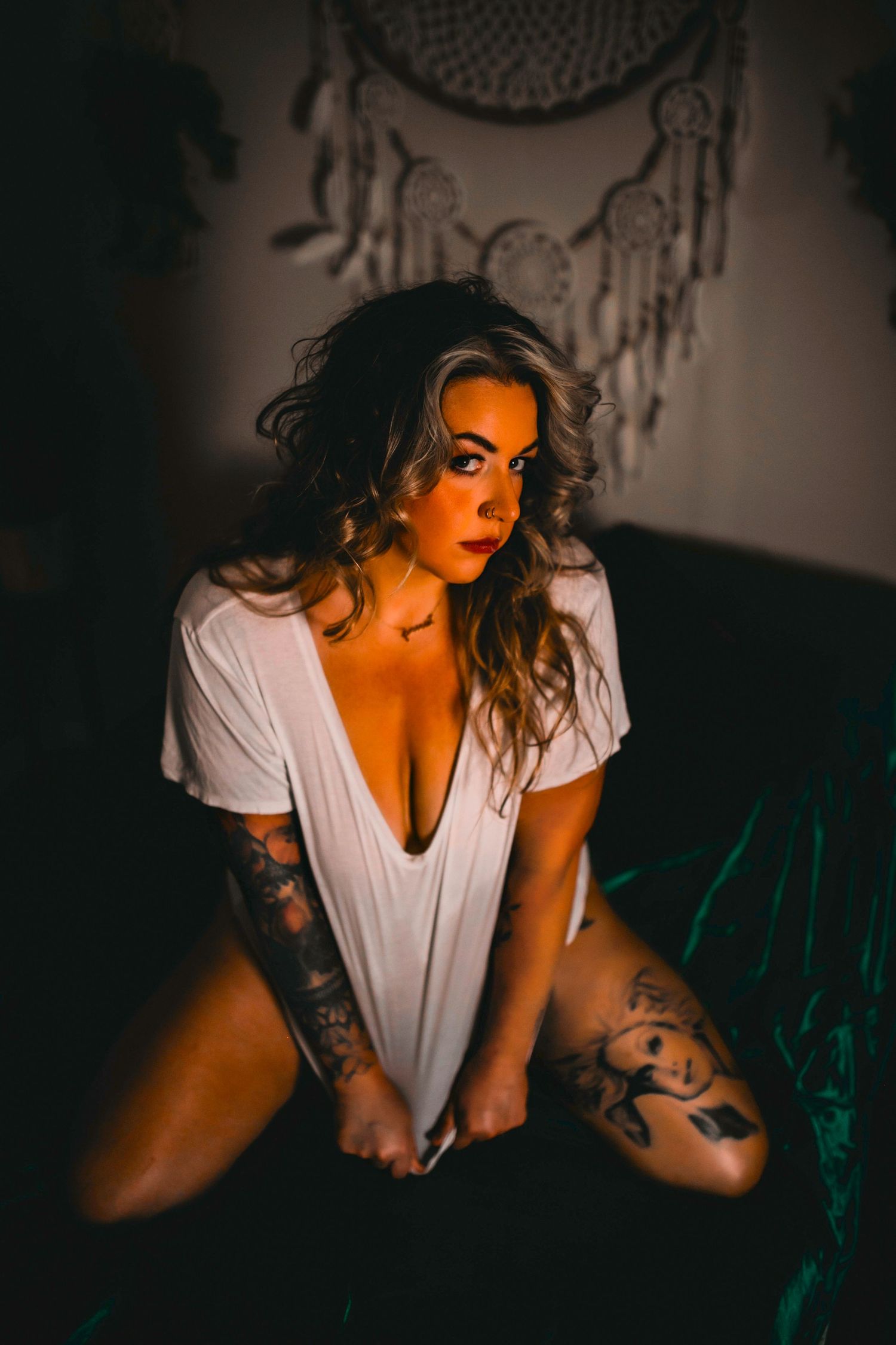 Intimate portrait with dreamcatcher decor and moody lighting.