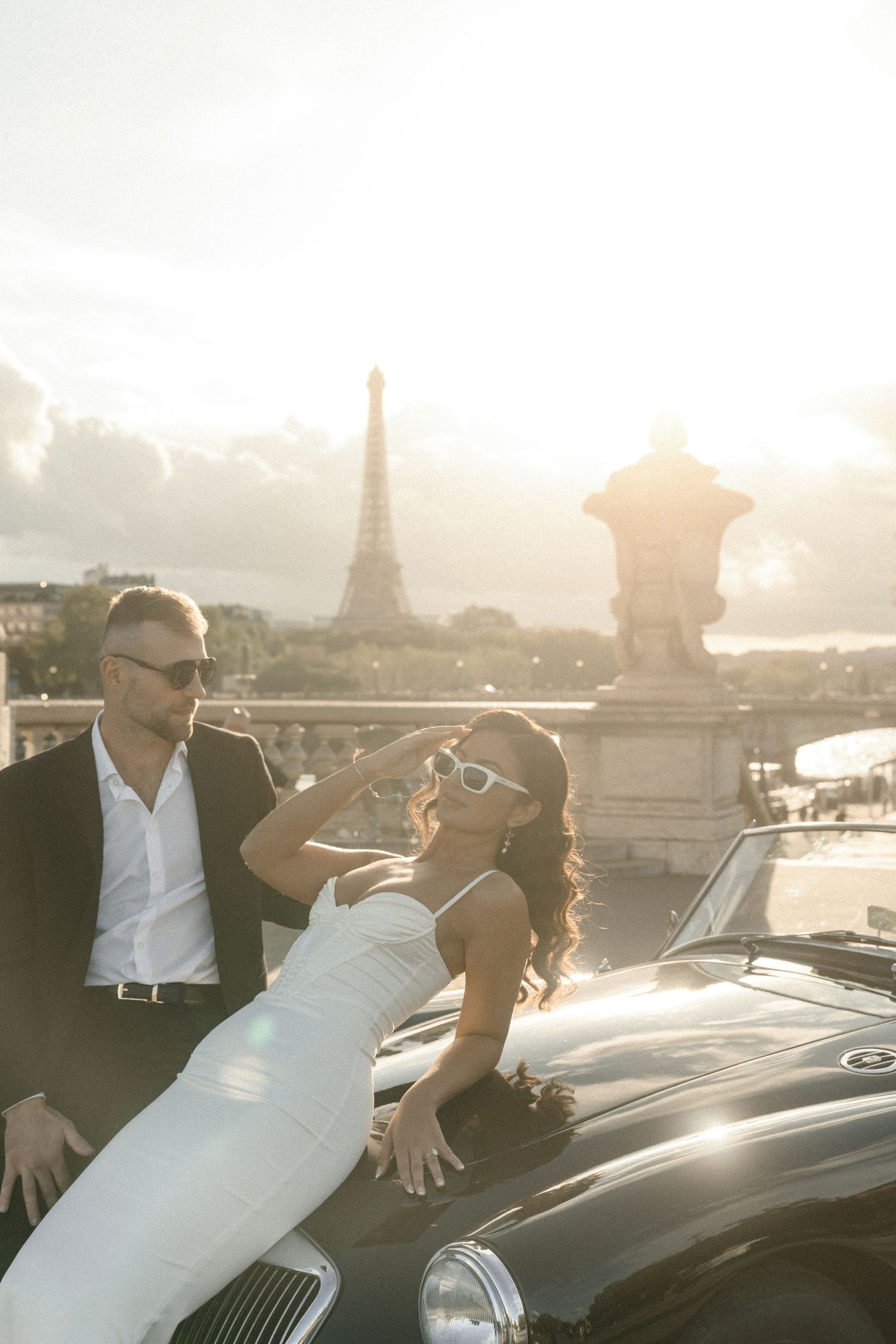 A vintage-inspired photoshoot with a classic car and the Eiffel Tower in the golden hour light.