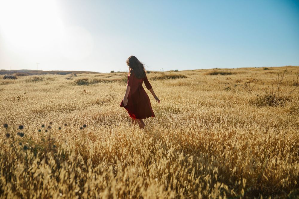 A magical image of a girl in a red dress walking in a golden field