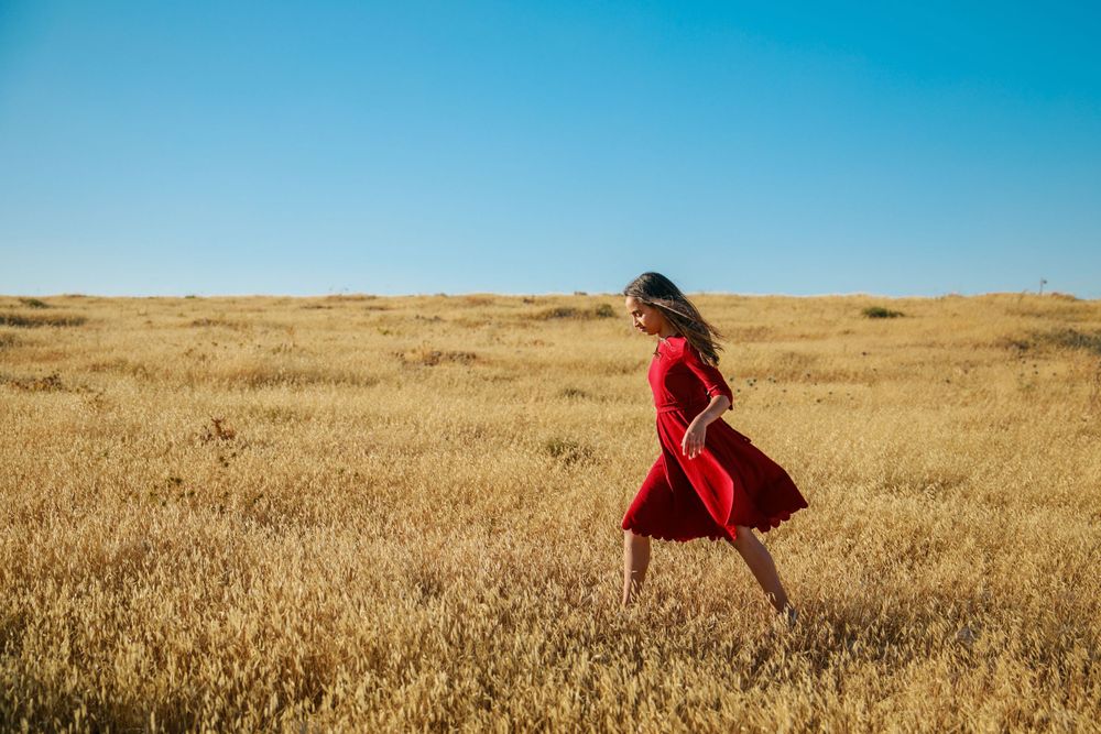 A magical image of a girl in a red dress walking in a golden field