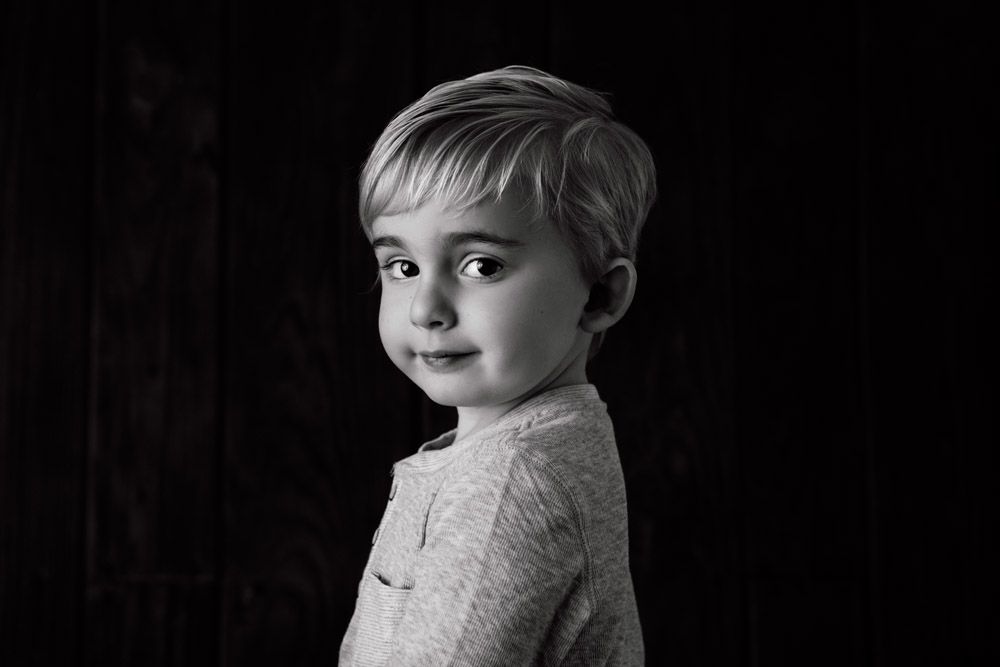 Dramatic black and white portrait with soft side lighting against dark background.