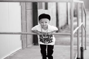 A child in black and white clothing stands in a walkway.