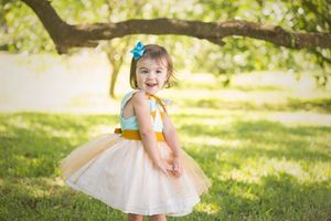 Toddler in tulle dress twirling in sunlit garden setting.