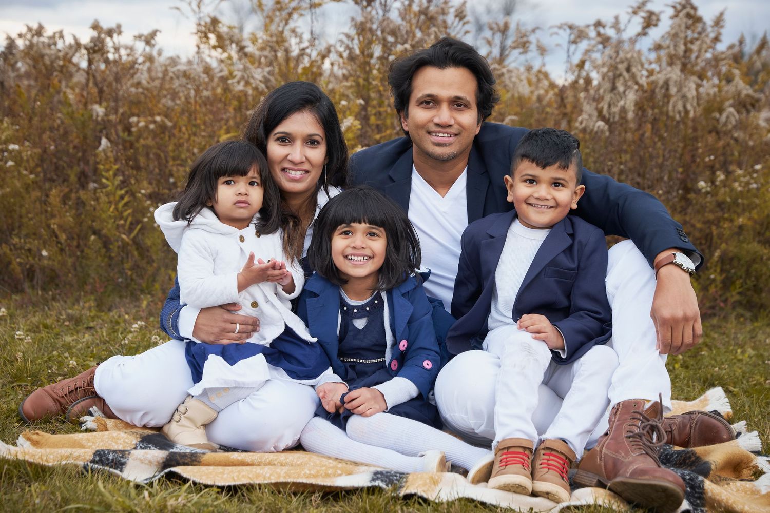 Family group lying on blanket outdoors during autumn photo session.