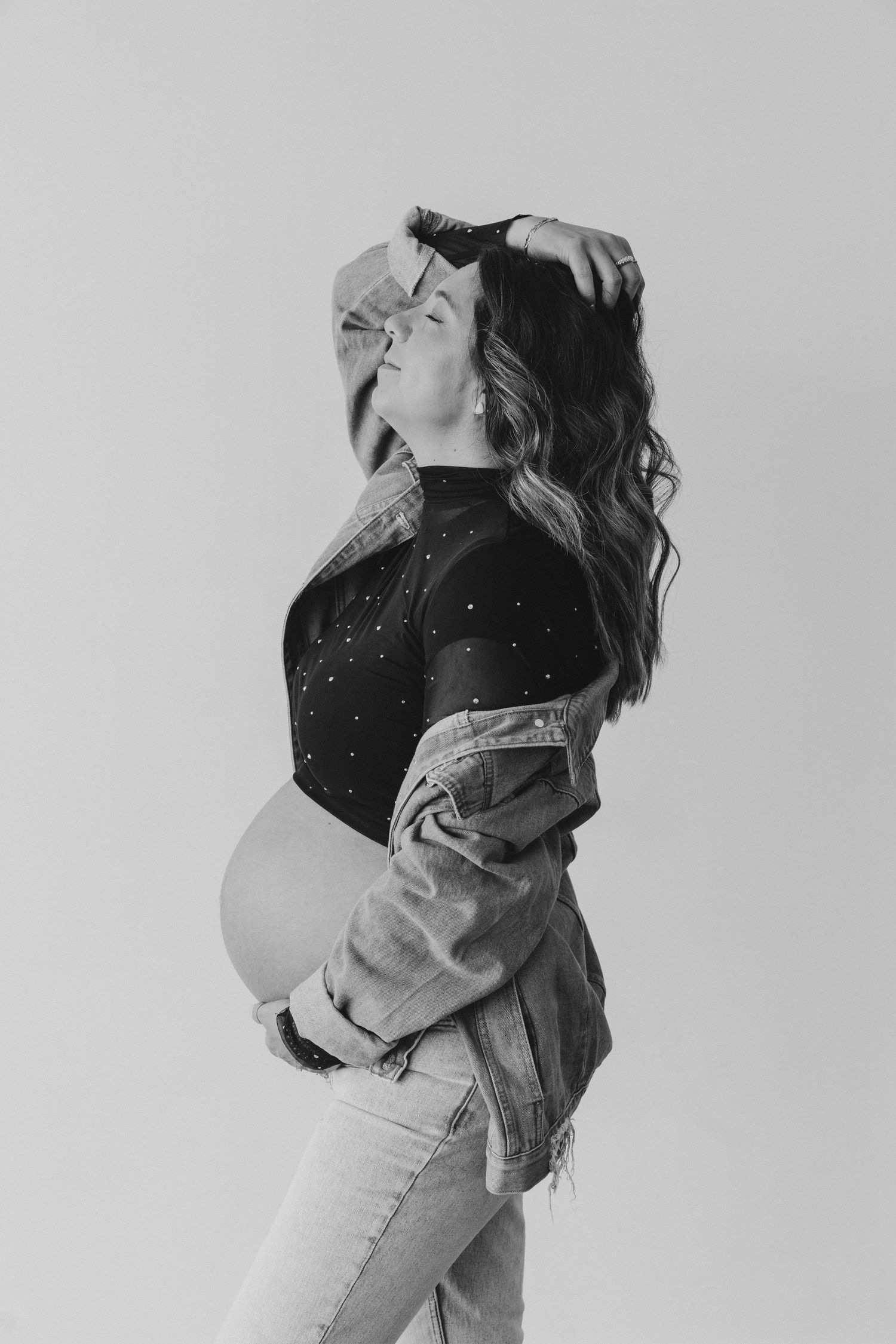 pregnant woman embracing belly maternity pose at a studio located in Richardson Texas