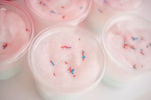 Close-up of pink cotton candy floss with blue and pink sprinkles.