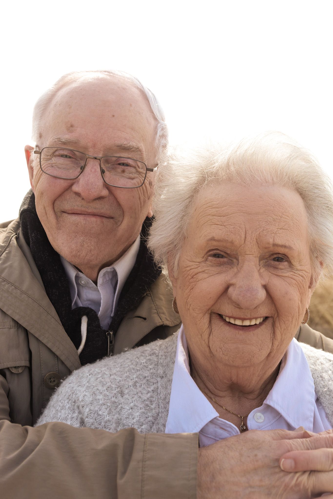 A series of close-up portraits showing an elderly couple smiling and embracing outdoors.