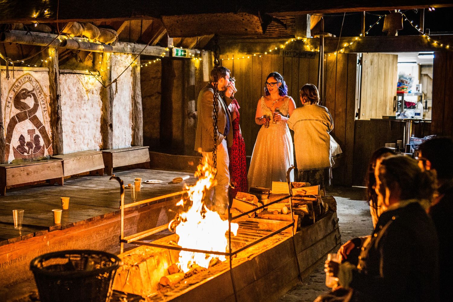 Fire cooking station with flames and food preparation at outdoor wedding reception.