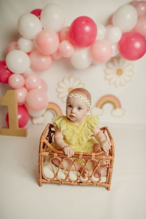 Birthday setup with pink balloon garland, rainbow decor, and woven basket prop.