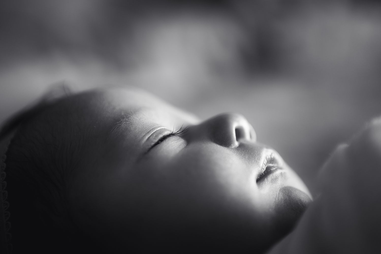 Newborn baby sleeping light shines on her eyelashes nose and little lips