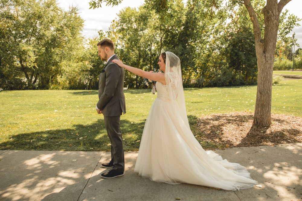 A bride surprises her groom during their first look wedding moment on a garden path.