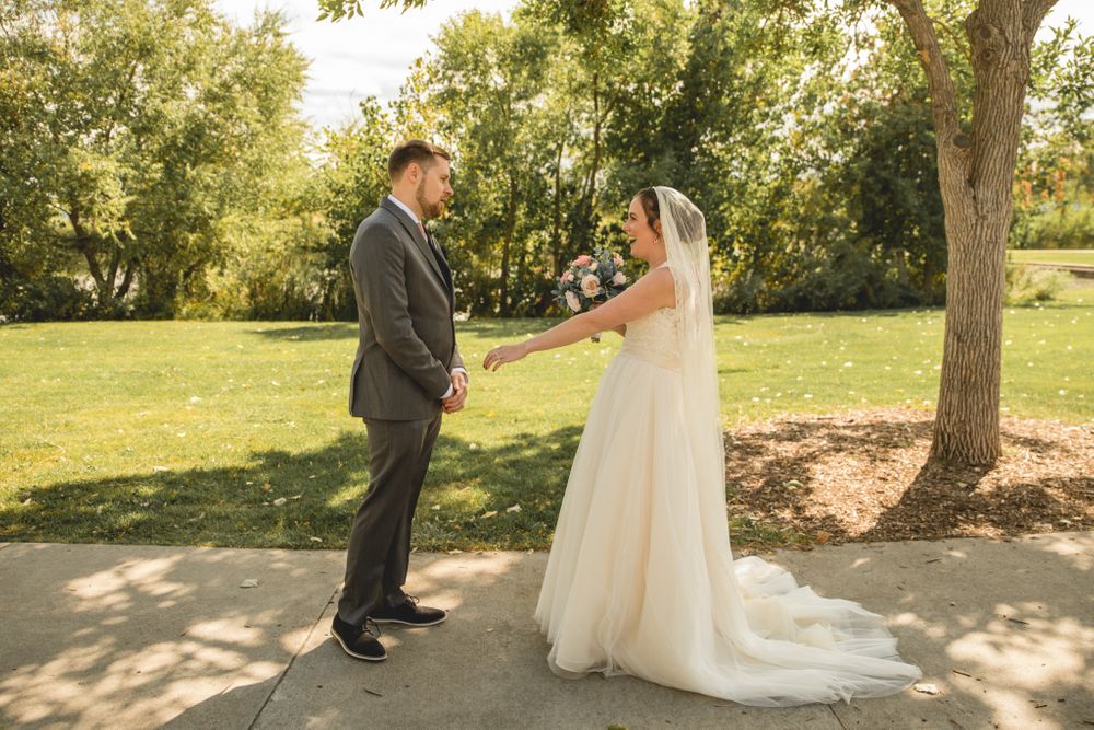 A sweet wedding moment captured between a bride and groom in a sunlit garden.