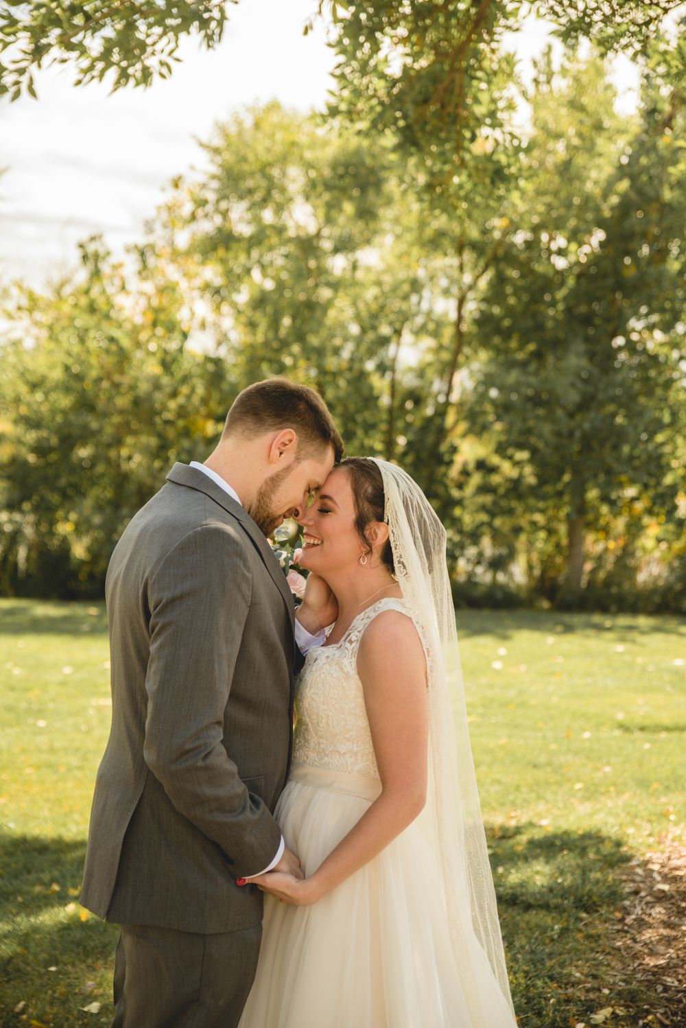 A tender moment between newlyweds in a sunlit garden with soft golden light.