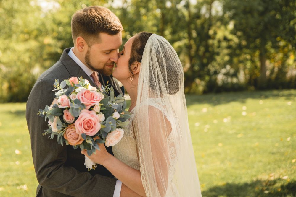 A romantic wedding portrait with pink rose bouquet in warm afternoon sunlight.
