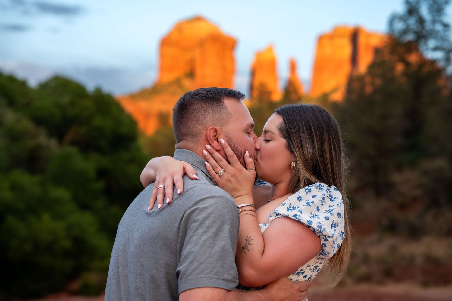A couple shares a romantic kiss against the backdrop of red rock formations in Sedona at sunset. Sedona Engagement Photography