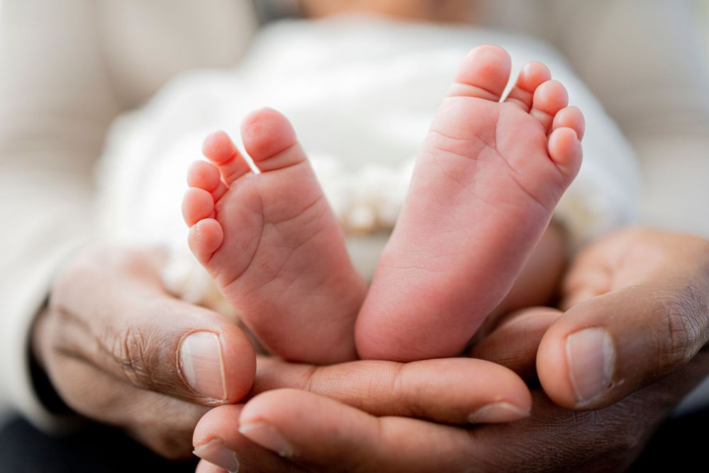 aurora at home newborn photoshoot, close up image of adult hands holding newborn feet