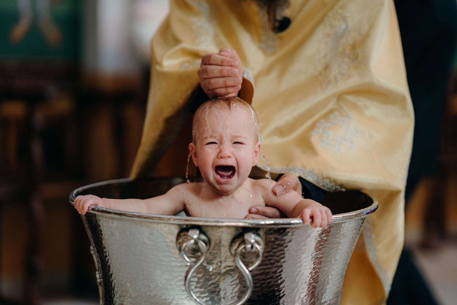 baby being baptised with water and crying