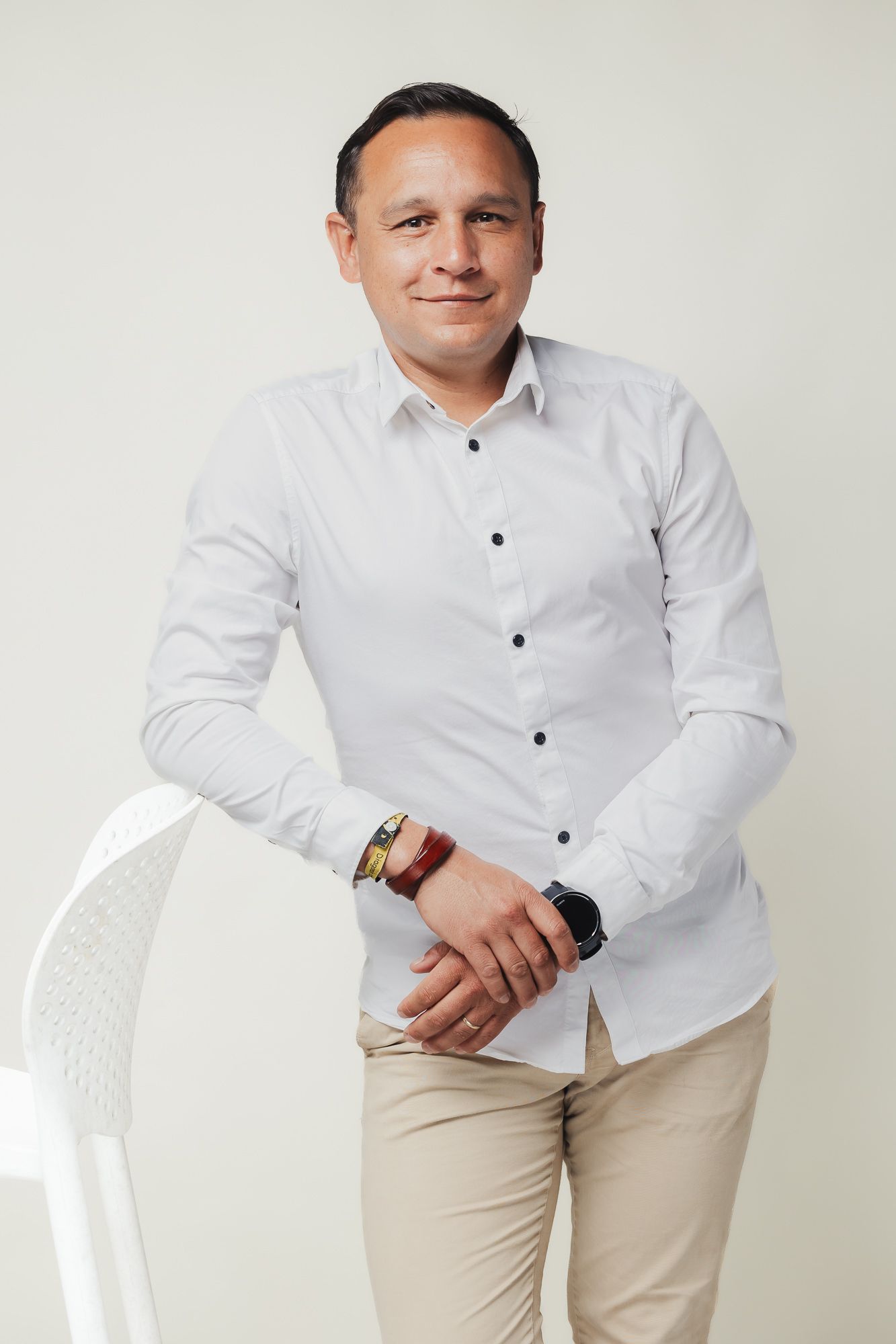 Professional portrait against white background in formal white shirt and khaki pants.