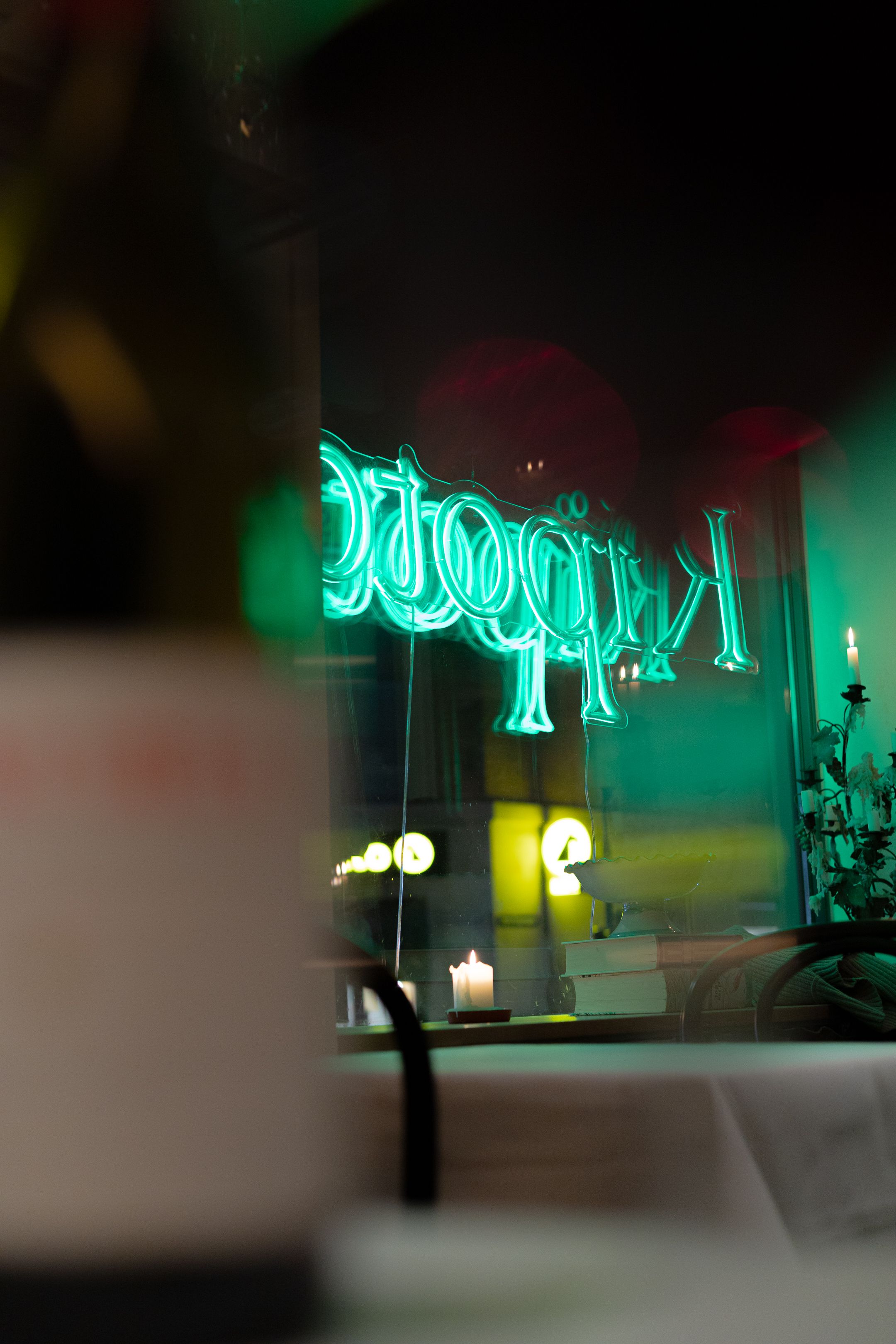 Atmospheric restaurant interior with glowing green neon signage in soft focus.