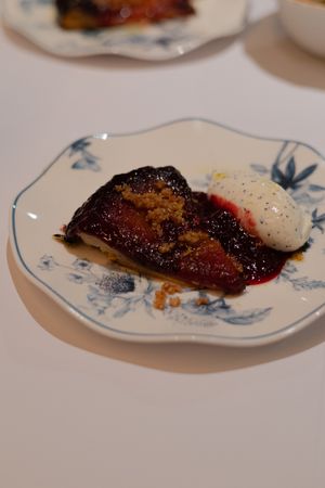 Seared fish with red sauce and cream on a blue and white porcelain plate.