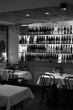 Elegant restaurant interior with white tablecloths and extensive wall-mounted wine bottle display.