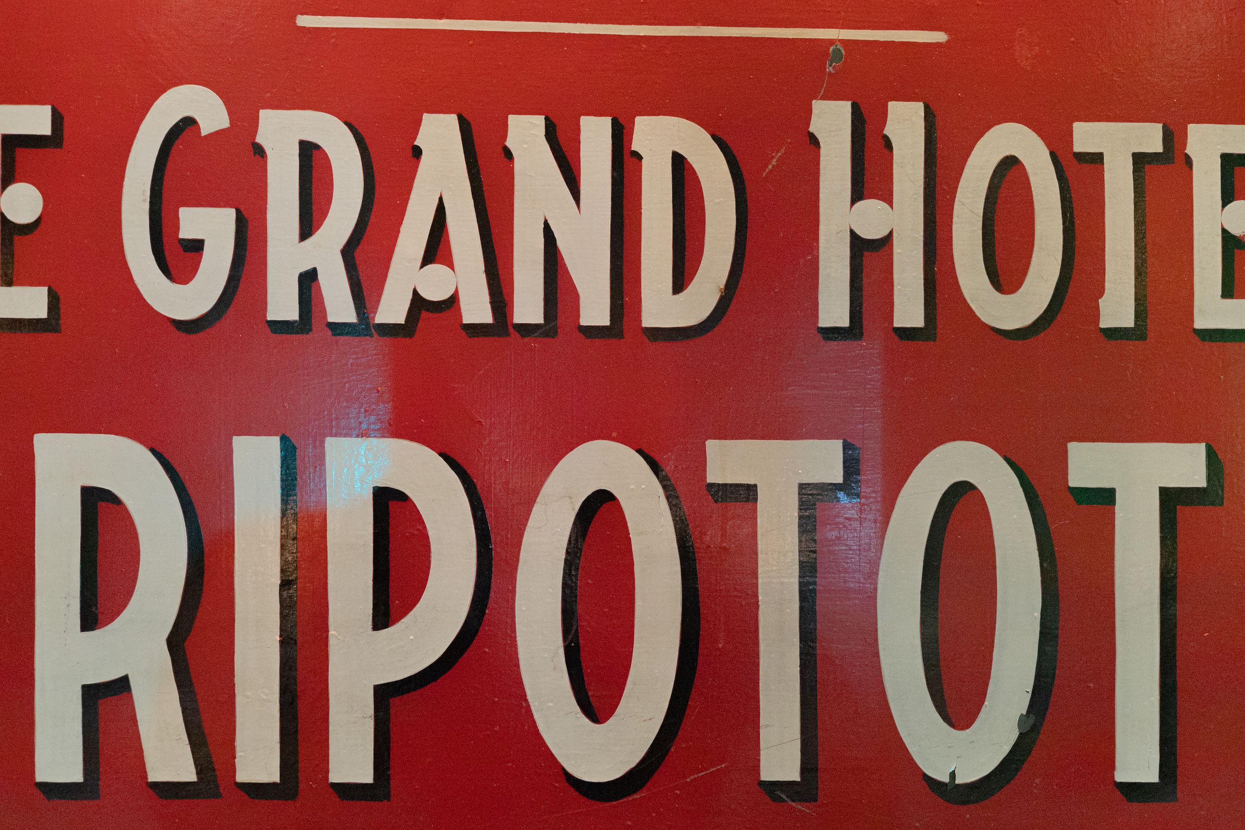 Red vintage hotel sign reading Le Grand Hotel Ripotot.