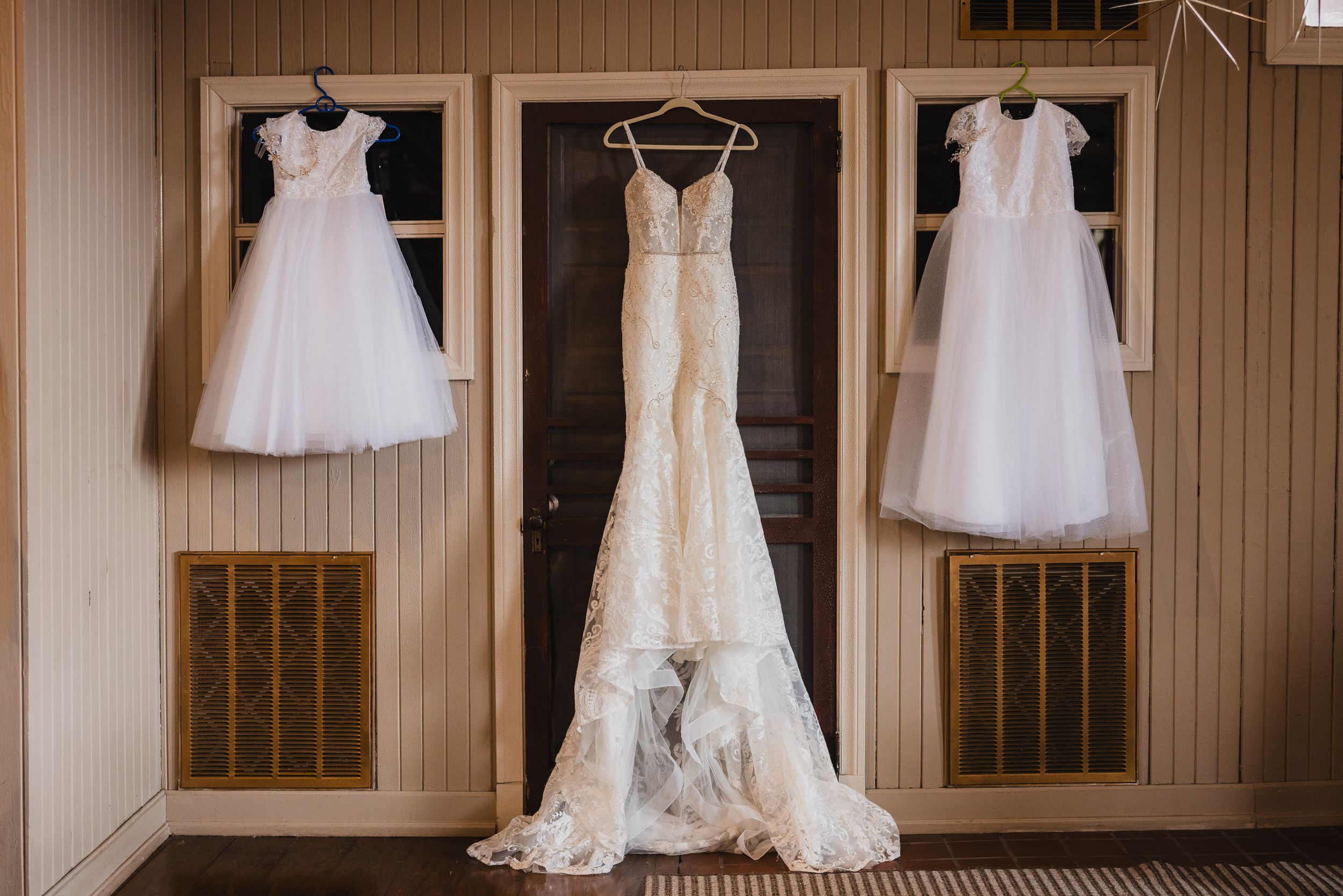 Wedding dresses displayed on hangers in a wooden-paneled bridal suite.