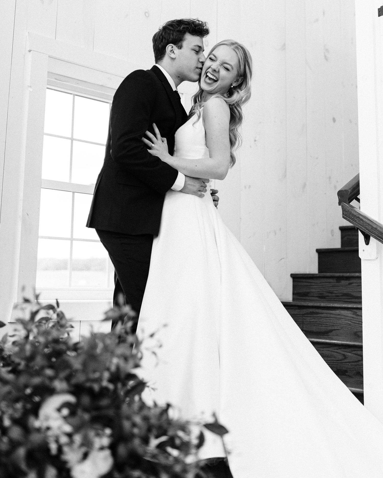 Black and white photo of couple sharing laughter on elegant staircase.