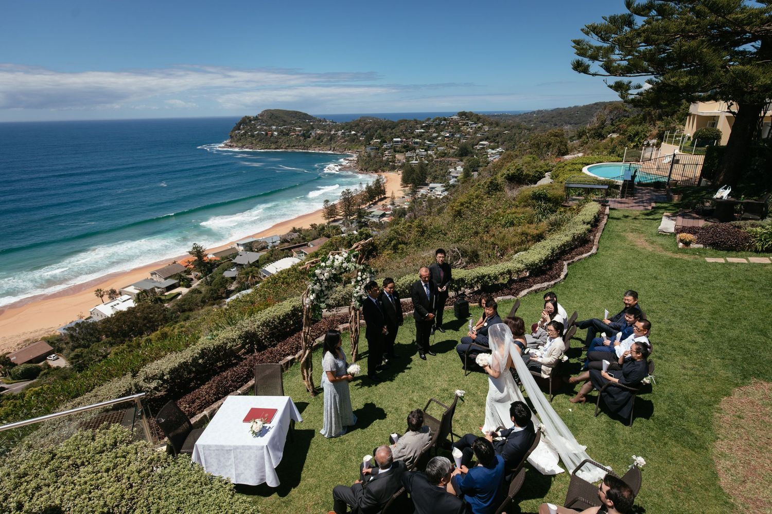 Stunning clifftop wedding ceremony overlooking Avalon Beach with ocean views and manicured garden setting.
