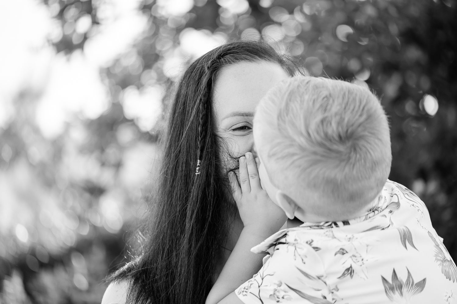 A tender black and white moment between two people sharing a laugh outdoors.