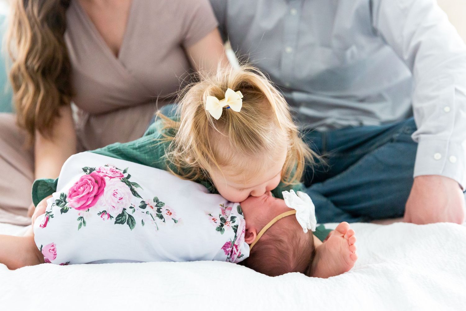 Sweet lifestyle photo of family moments on white bedding with floral outfit details.