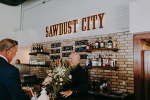 Interior view of rustic venue with 'Sawdust City' signage on brick wall.