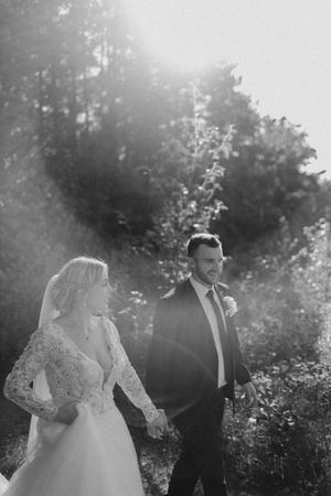 Dreamy backlit wedding portrait in natural setting with soft sunlight filtering through trees.