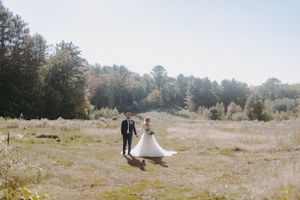 Wedding couple poses in a scenic outdoor field during golden hour.