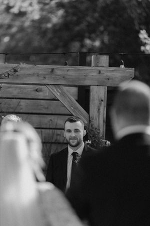 Black and white close-up shot of wedding ceremony attendees with wooden fence backdrop.