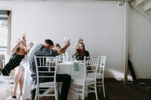 Modern white wedding reception venue with elegant table settings and chairs.