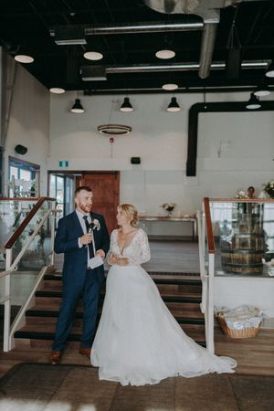 Wedding couple dances in spacious venue with white walls and wooden floors.