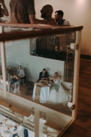 Wedding reception reflected in decorative mirror showing dining tables and guests.