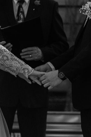Close-up black and white photo of hands during a wedding ceremony exchange.