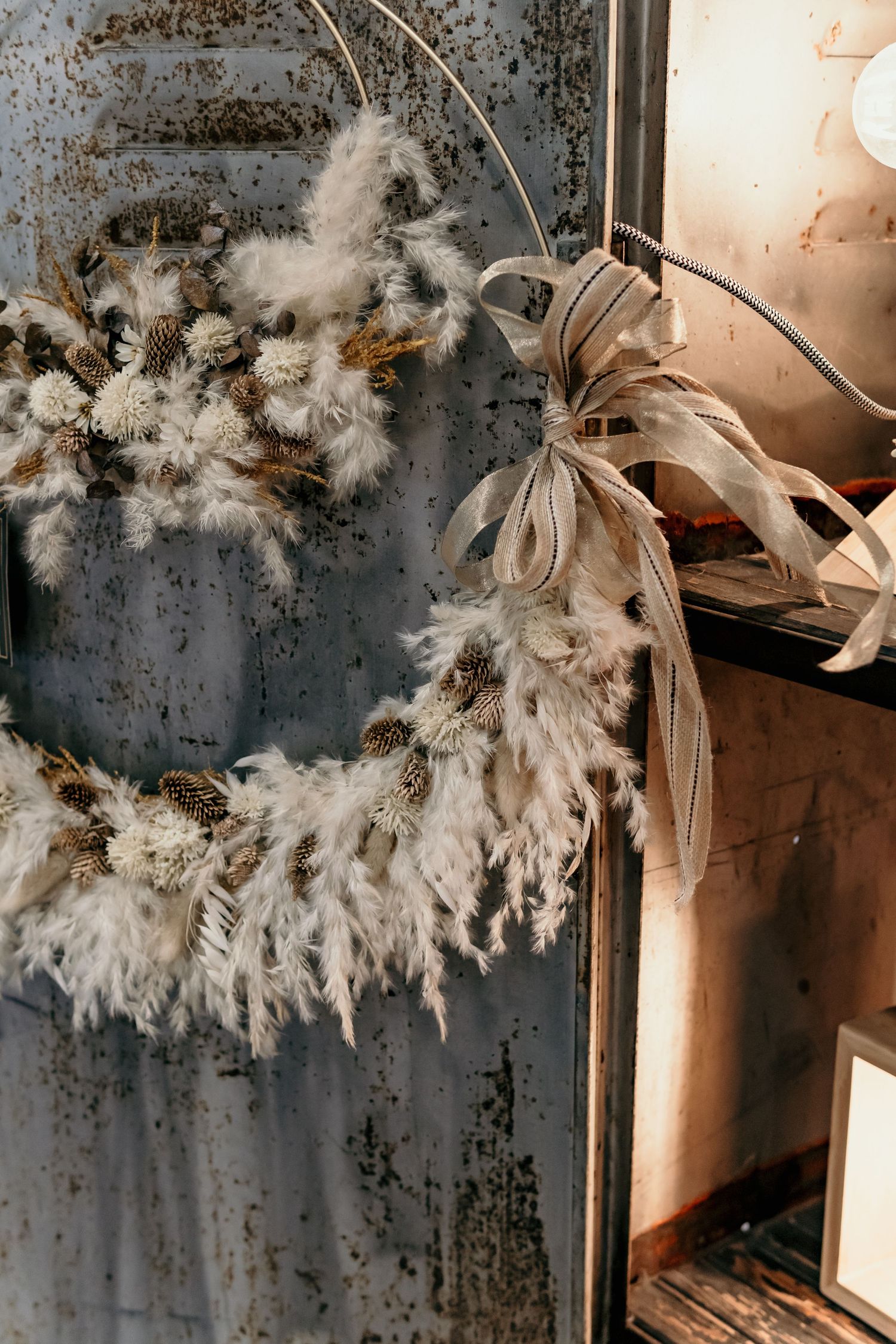 Dried pampas grass and floral arrangements creating ethereal display against textured wall.