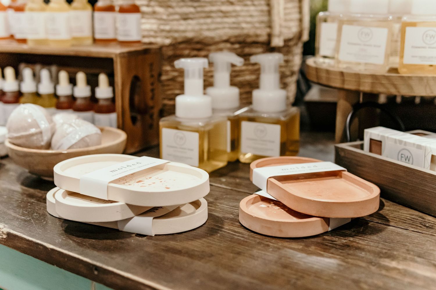 Handcrafted bath and beauty products displayed on wooden shelves in warm lighting.