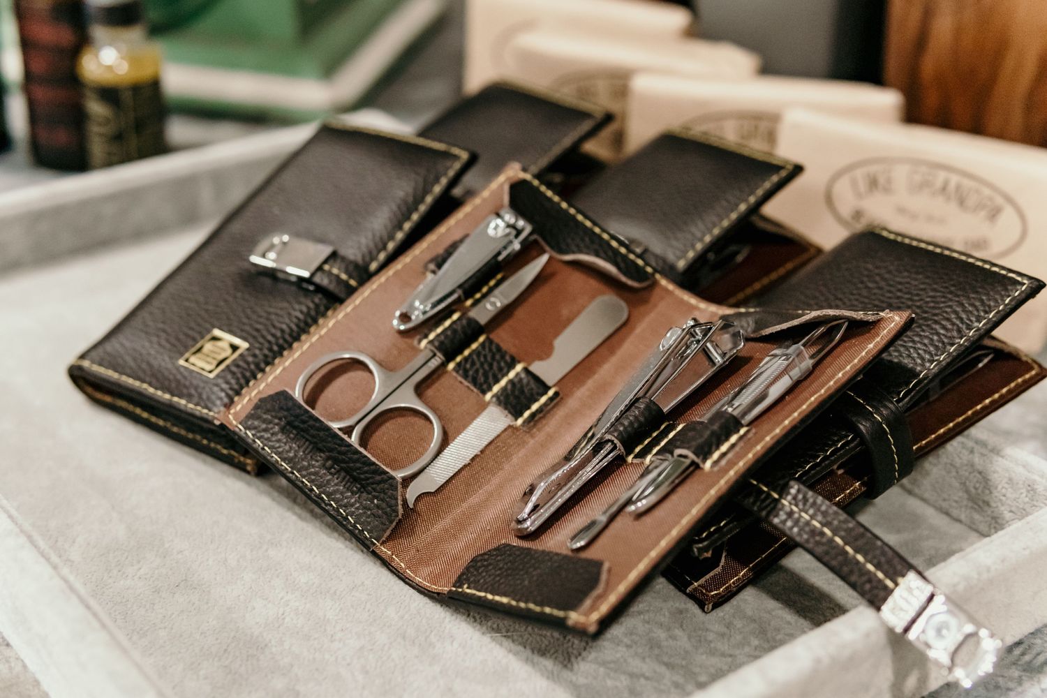 Leather grooming kit with professional tools and accessories laid out on gray surface.