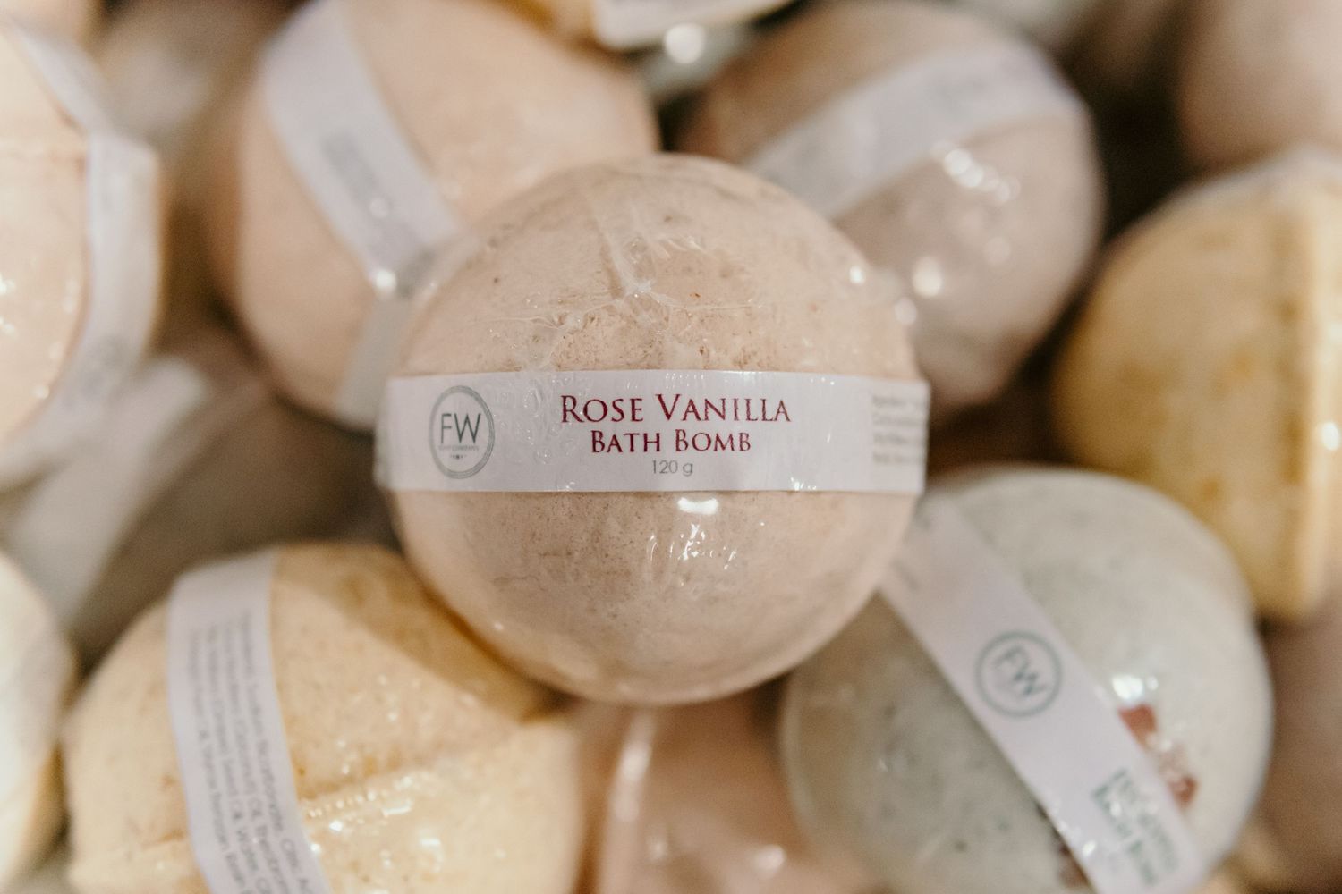 Rose vanilla bath bombs and beauty products arranged in soft, neutral tones.
