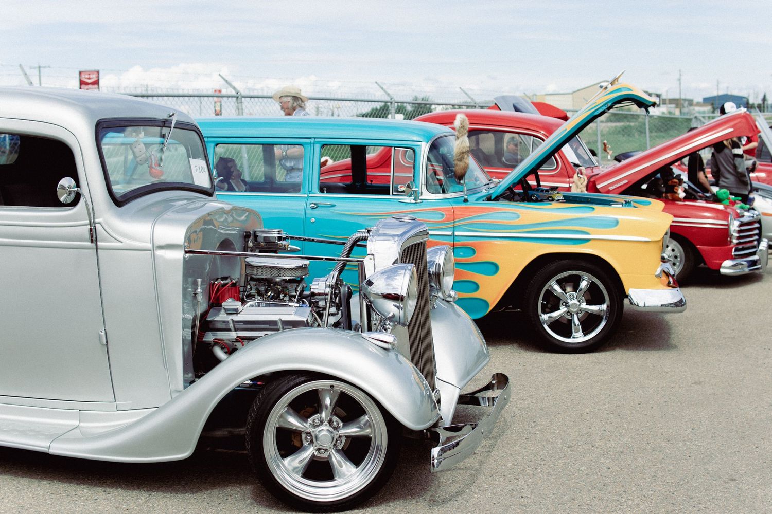 A row of vintage classic cars lined up at an outdoor auto show.